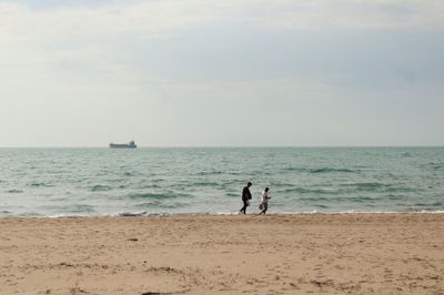 Two friends walking along a calm beach