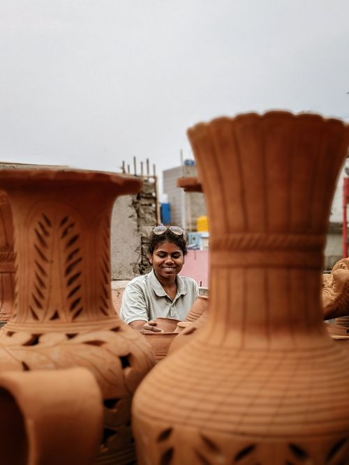 Free Smiling artisan crafting handmade ceramic pots in an outdoor setting. Stock Photo