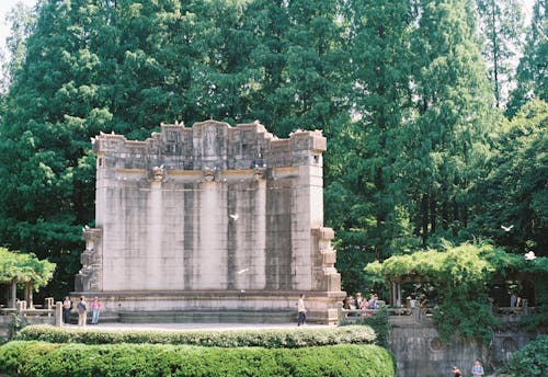 A monument in the middle of a park surrounded by trees