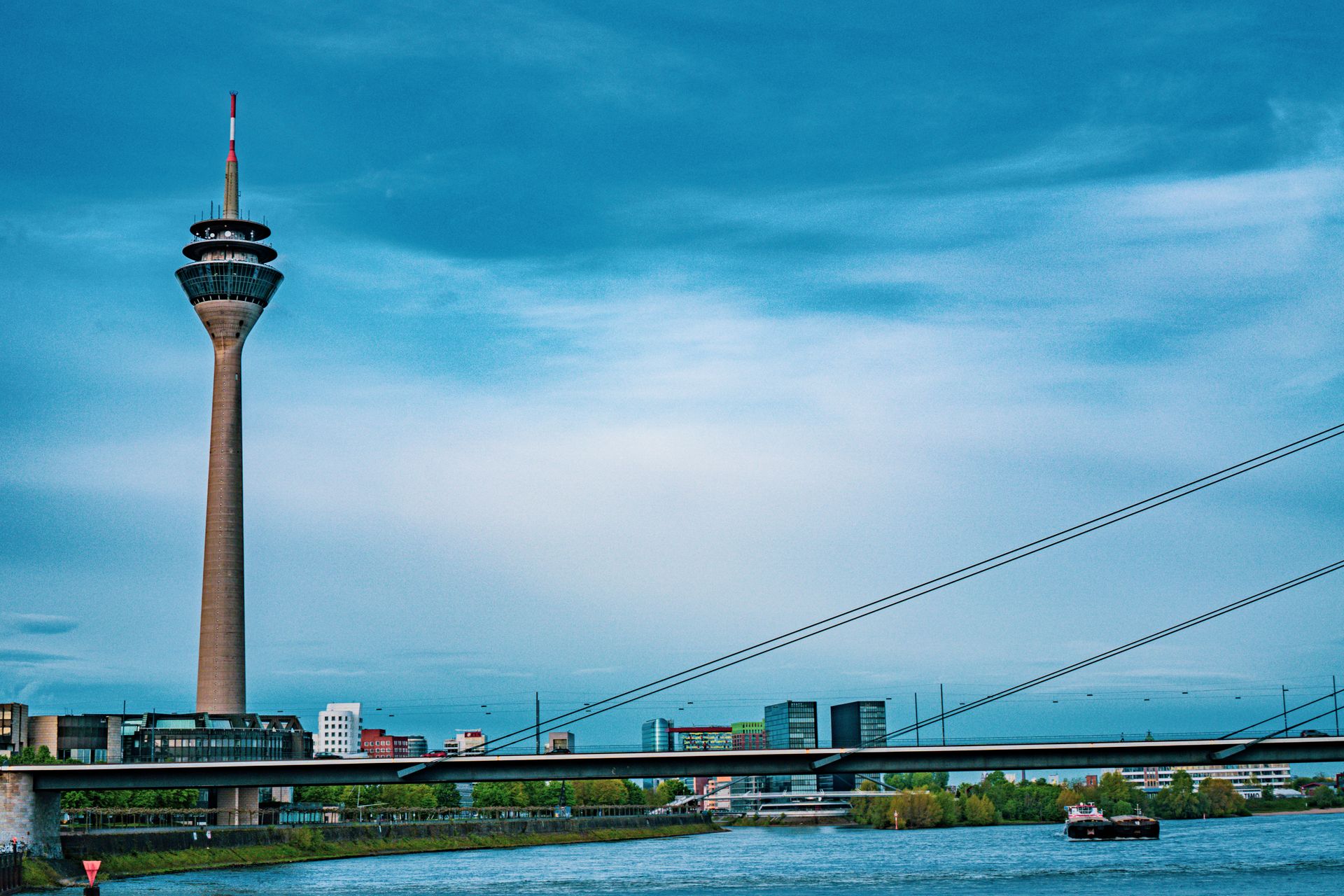 Scenic view of Düsseldorf's Rhine Tower and bridge over river under a clear blue sky.