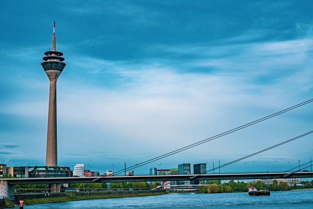 Scenic view of Düsseldorf's Rhine Tower and bridge over river under a clear blue sky.