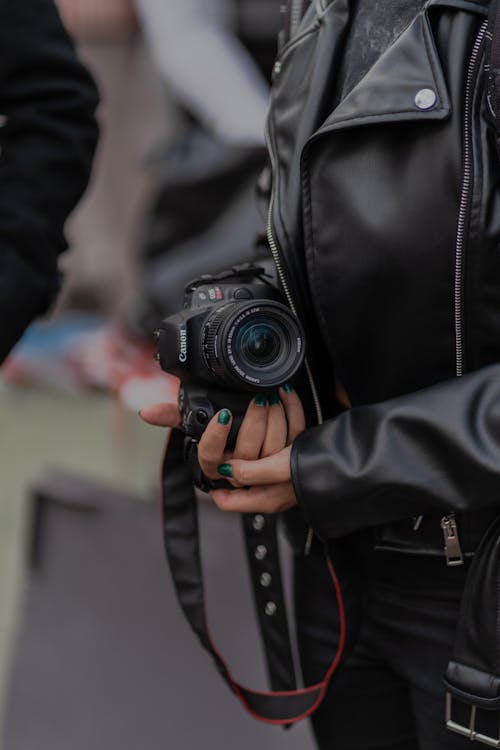 A woman in a leather jacket holding a camera