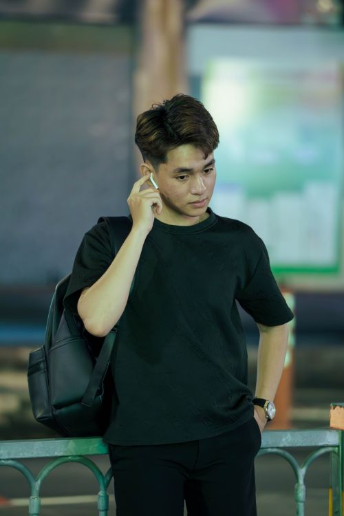 Free Portrait of a young man with earpods and backpack in an urban environment at night. Stock Photo