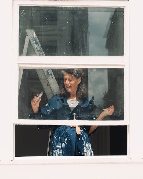 A woman in a blue dress is looking out of a window
