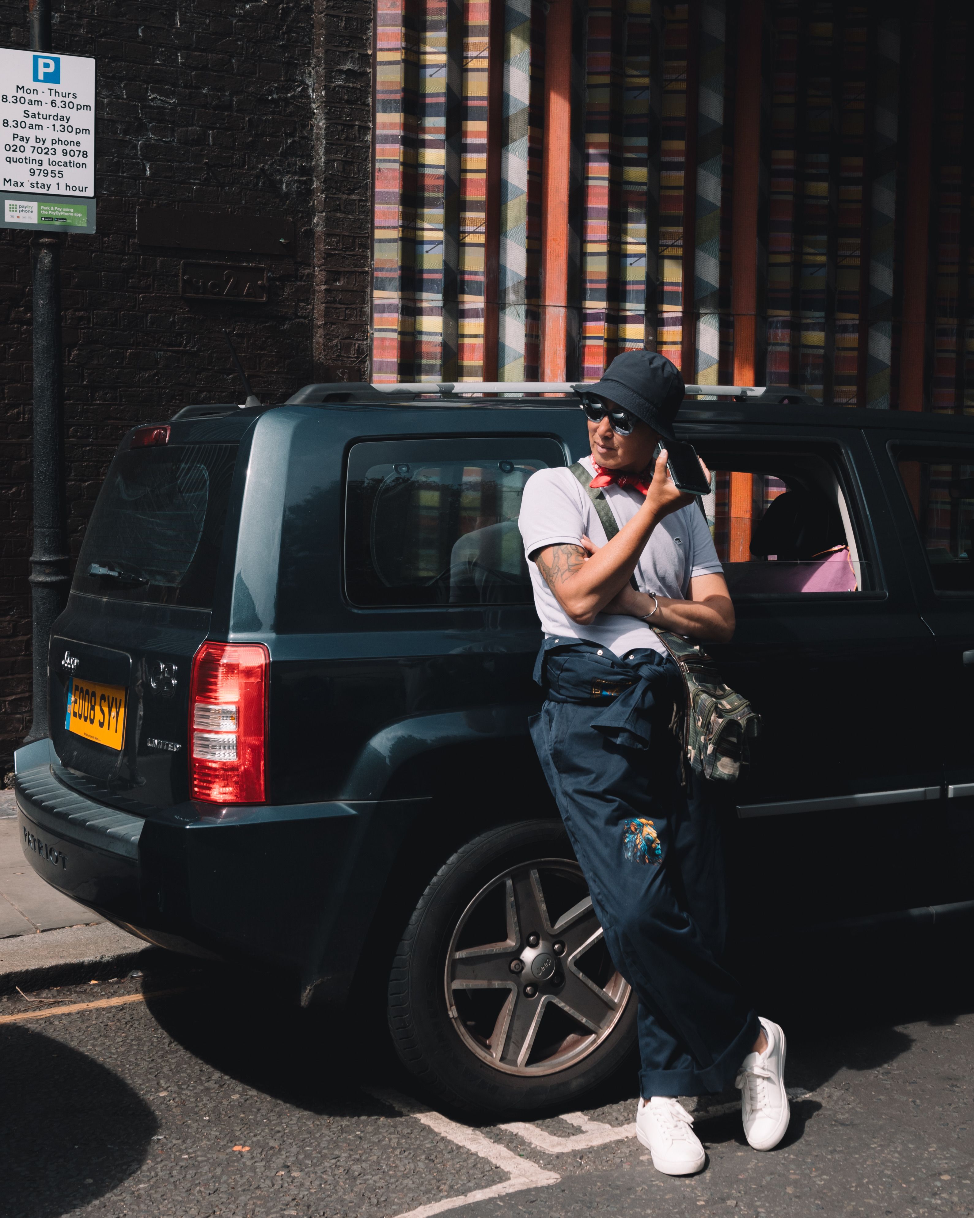 Stylish person posing by a car on lively urban street, embracing modern city vibe.