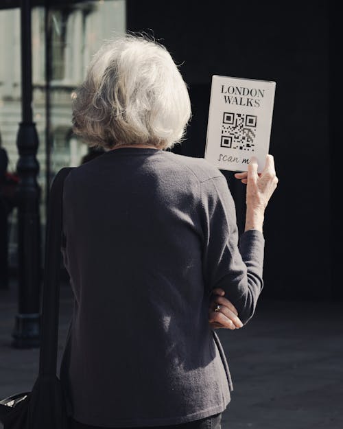 An older woman holding a qr code