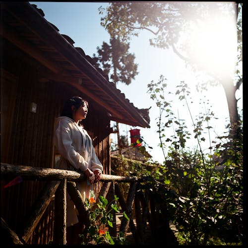 A woman standing on a wooden porch looking out at the sun