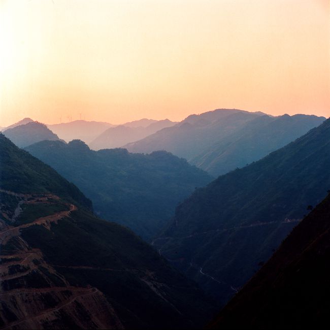 Breathtaking aerial view of layered mountains during sunset with a warm sky.