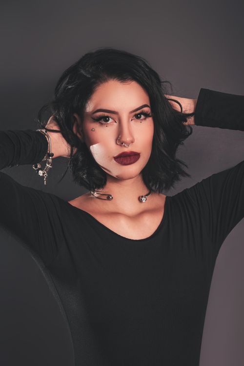 Free Sophisticated portrait of a stylish woman with black hair and piercing in a studio setting. Stock Photo