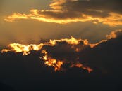 日落景象充满戏剧性，橙色的云层活力四射，阳光从中倾泻而出