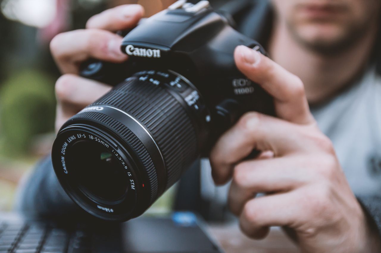 a close up of a person using a dslr camera highlighting the lens and h