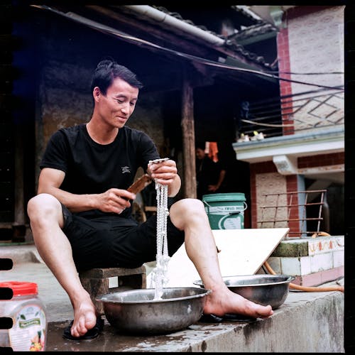 A man sitting on a bench with a bowl of water