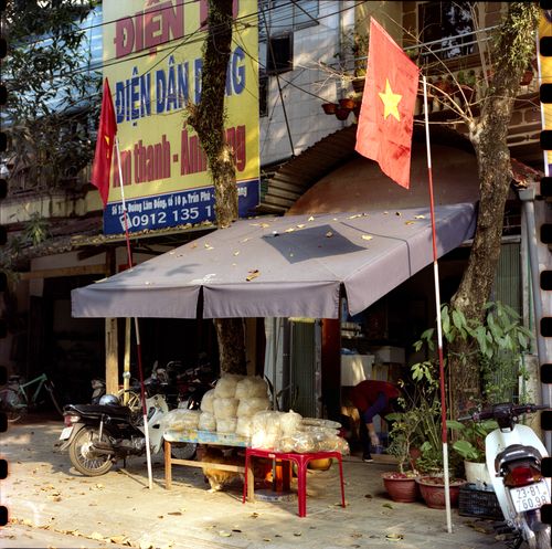 Free Vietnamese street with motor scooters, flags, and a small storefront. Stock Photo