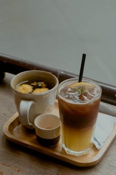 Warm herbal tea and iced citrus coffee served on a tray, showcasing a cozy still life.