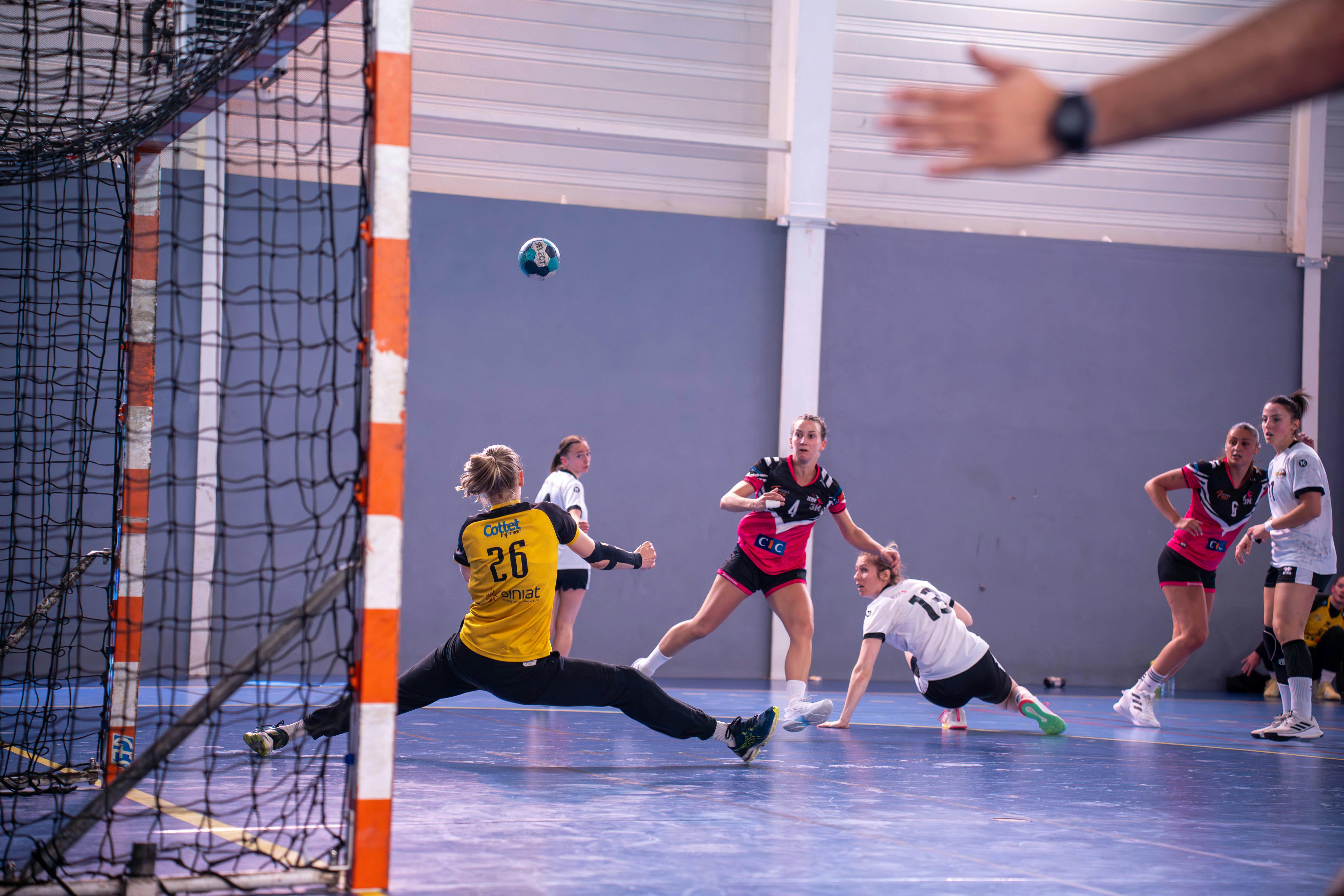 Competitive Handball Players In Action On A Court, Showcasing Sprinting, Jumping, And Teamwork During A Match