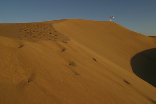 Photo De Paysage D'un Homme Debout Sur Une Dune De Sable Dans Un Désert