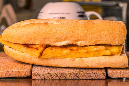 Close-up of a tasty Spanish omelette filled baguette on a wooden board.