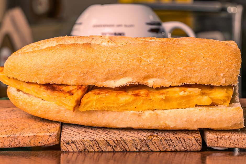 Close-up of a tasty Spanish omelette filled baguette on a wooden board.