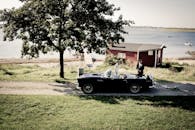 新郎新娘开着老爷车在湖畔，婚礼现场完美