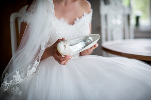 Mulher Em Vestido De Noiva Branco Segurando Sapato De Couro Branco Não Emparelhado