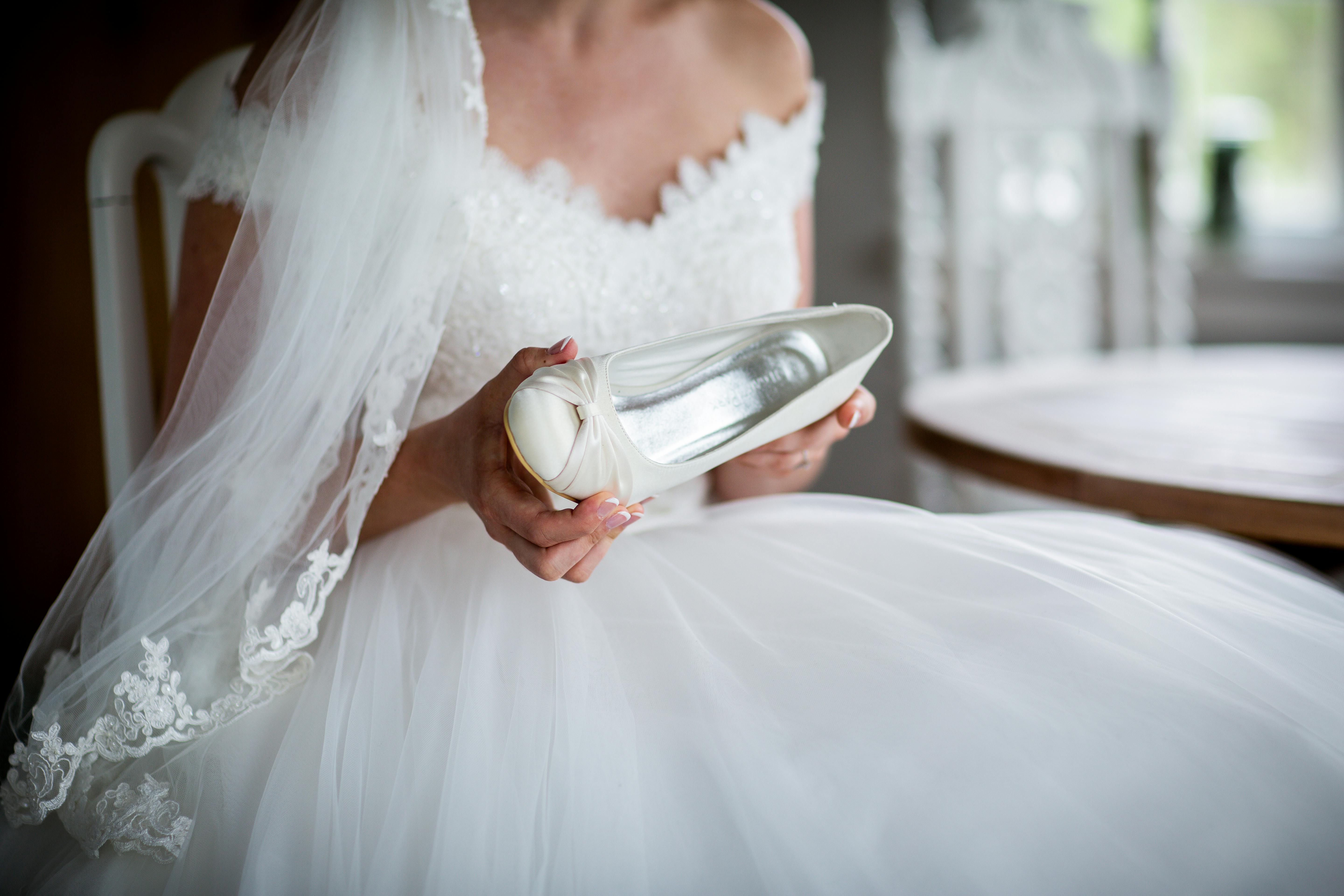 Woman In White Wedding Dress Holding Unpaired White Leather Shoe