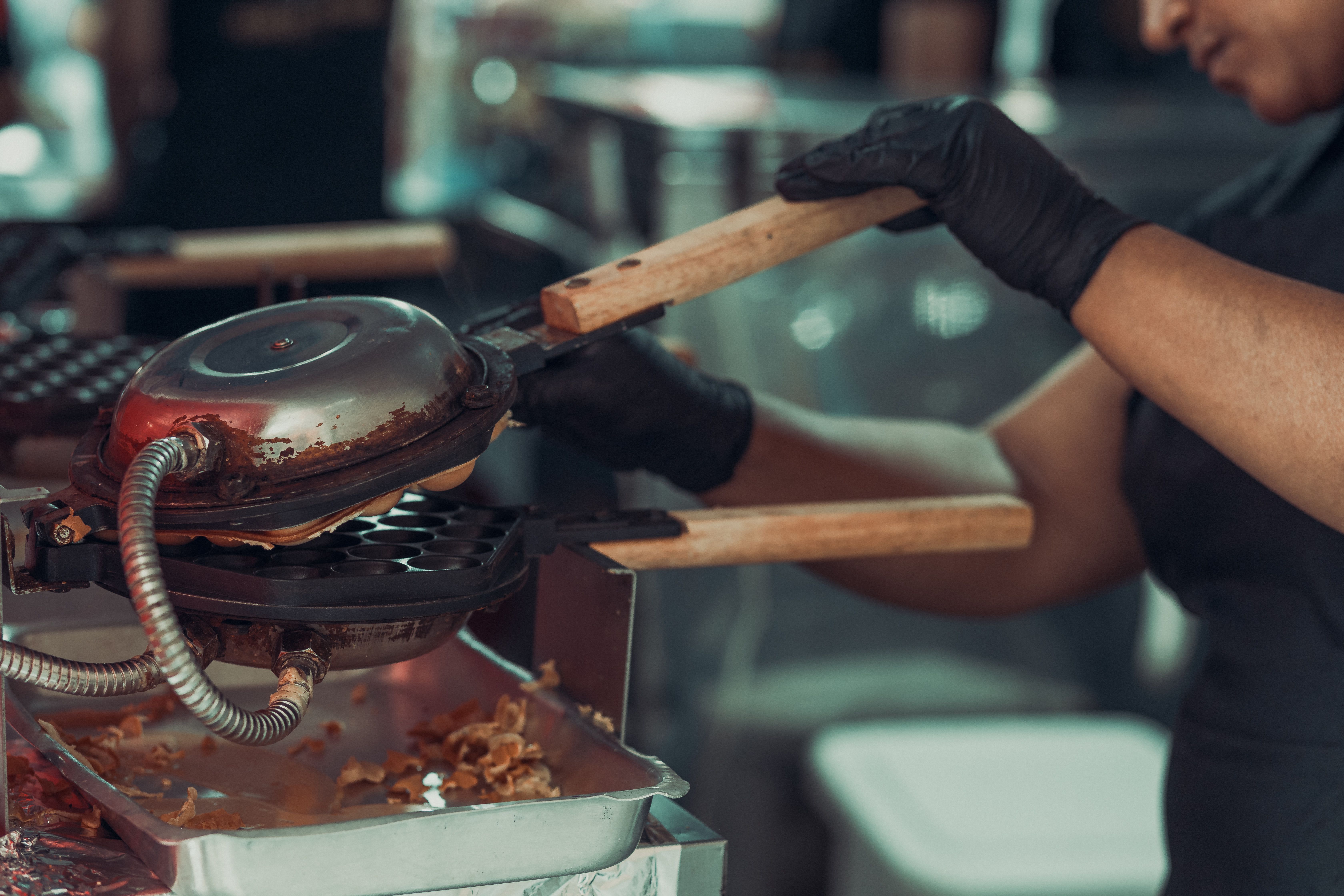 A chef using a waffle iron to cook fresh waffles in a professional kitchen.