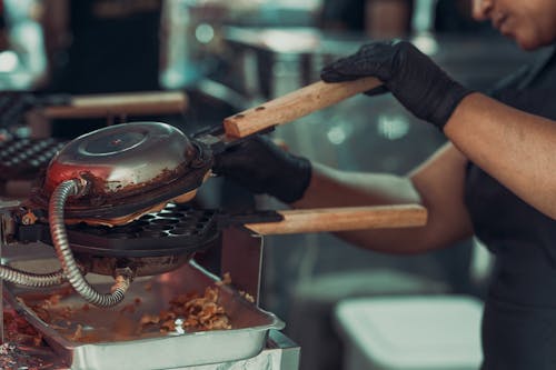 A woman in black gloves is cooking food in a kitchen