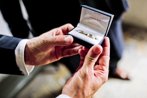 Foto Orang Yang Memegang Kasing Hitam Putih Dengan Dua Cincin Emas