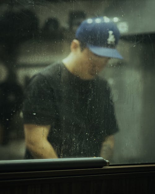 A man in a baseball cap looking out the window