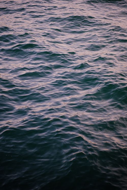 Free A serene view of rippling ocean waves captured at sunset with soft light and shadow play. Stock Photo