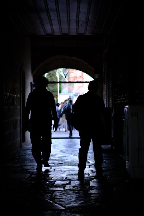 Free Silhouette view of people walking through a dimly lit urban tunnel. Stock Photo