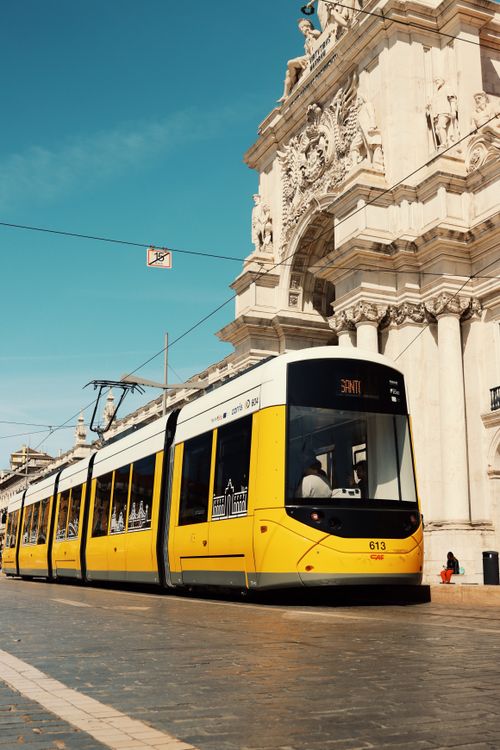 Free Capture of Lisbon's famous yellow tram passing by the historic Praça do Comércio. Stock Photo