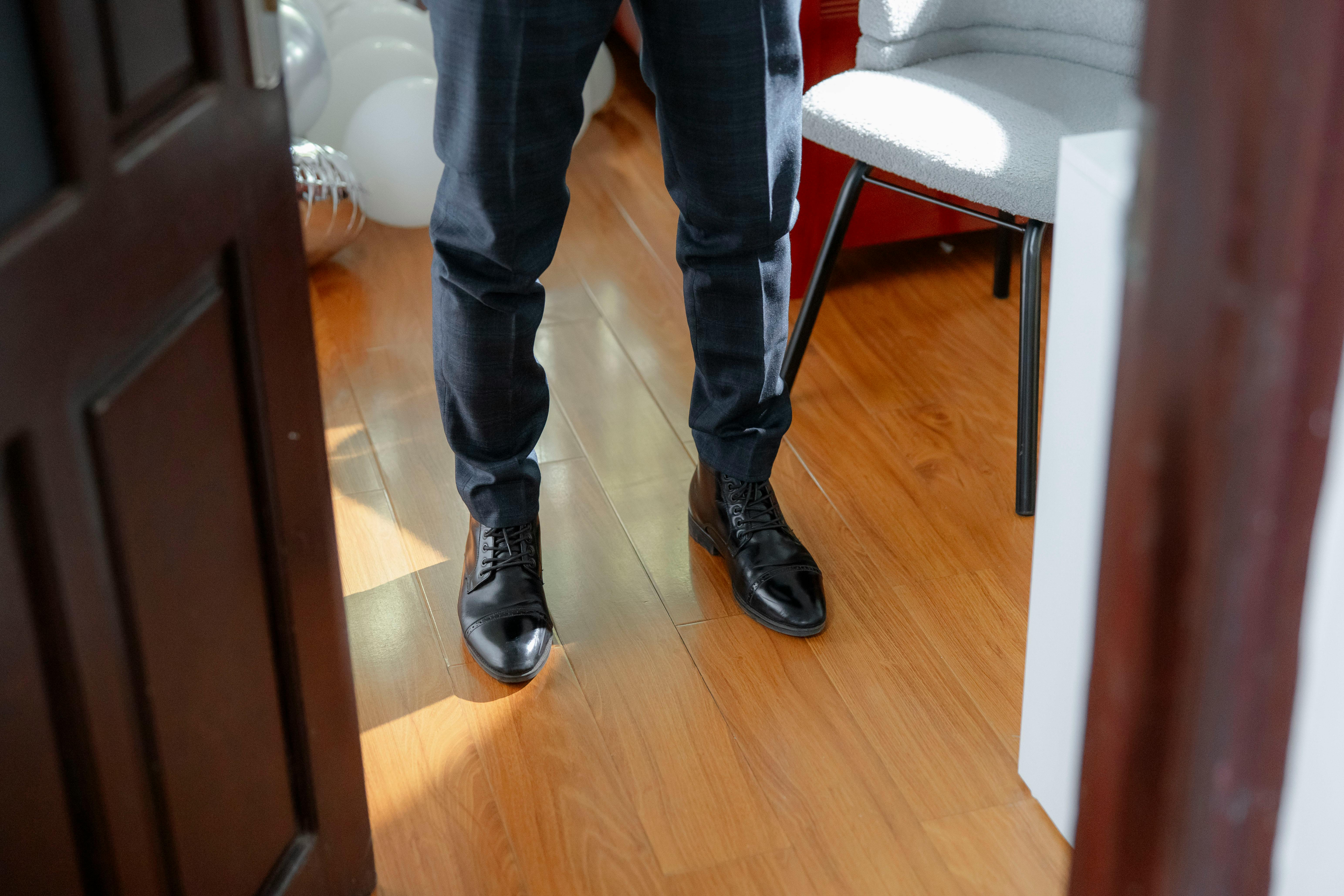A close-up of a man in formal attire standing on a wooden floor, creating a sophisticated and elegant vibe.