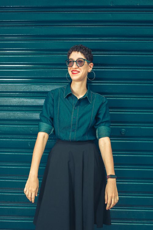 Free Fashionable woman in a jean shirt and skirt smiling against a blue background. Stock Photo