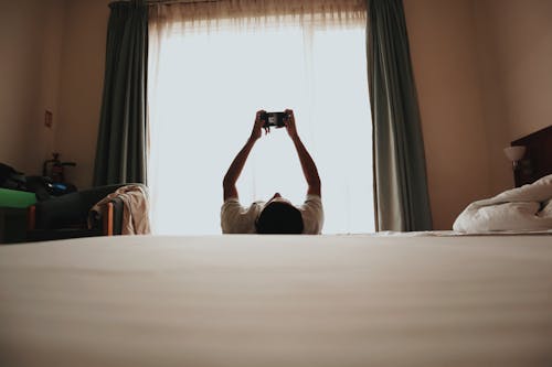 A person laying on their bed with their arms up