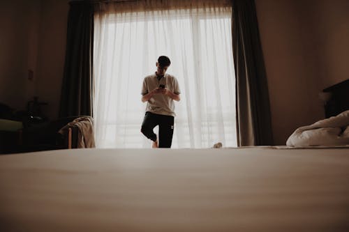 A man standing in front of a bed with a window