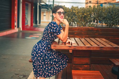 Free Woman with short hair and sunglasses enjoying outdoors at a city café. Stock Photo