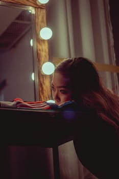 一幅梦幻般的肖像，描绘了一位亚洲妇女在光线昏暗的房间里凝视着发亮的镜子