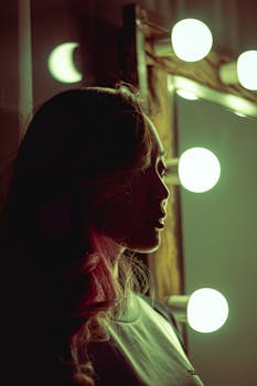 一名女子闷闷不乐地坐在发光的梳妆镜前，只留下一个剪影