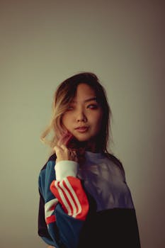 一位年轻女子穿着彩色运动衫，在艺术肖像中带着沉思的表情看向别处