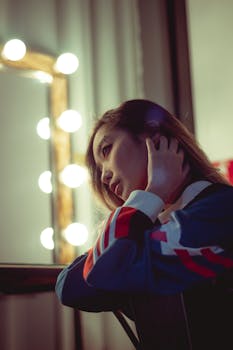 Close-up of a young woman posing indoors with soft lighting and a reflective expression.
