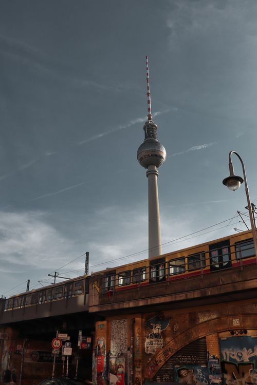 Free Photo of Berlin's TV Tower and a train passing by during sunset, capturing urban and transportation themes. Stock Photo