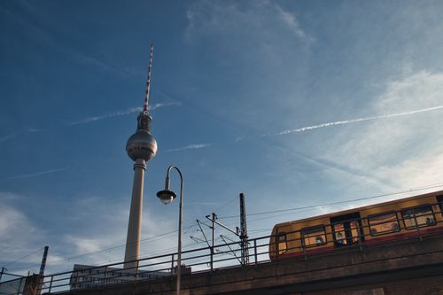 Free Capture of Berlin's Fernsehturm tower and train against a clear blue sky. Stock Photo