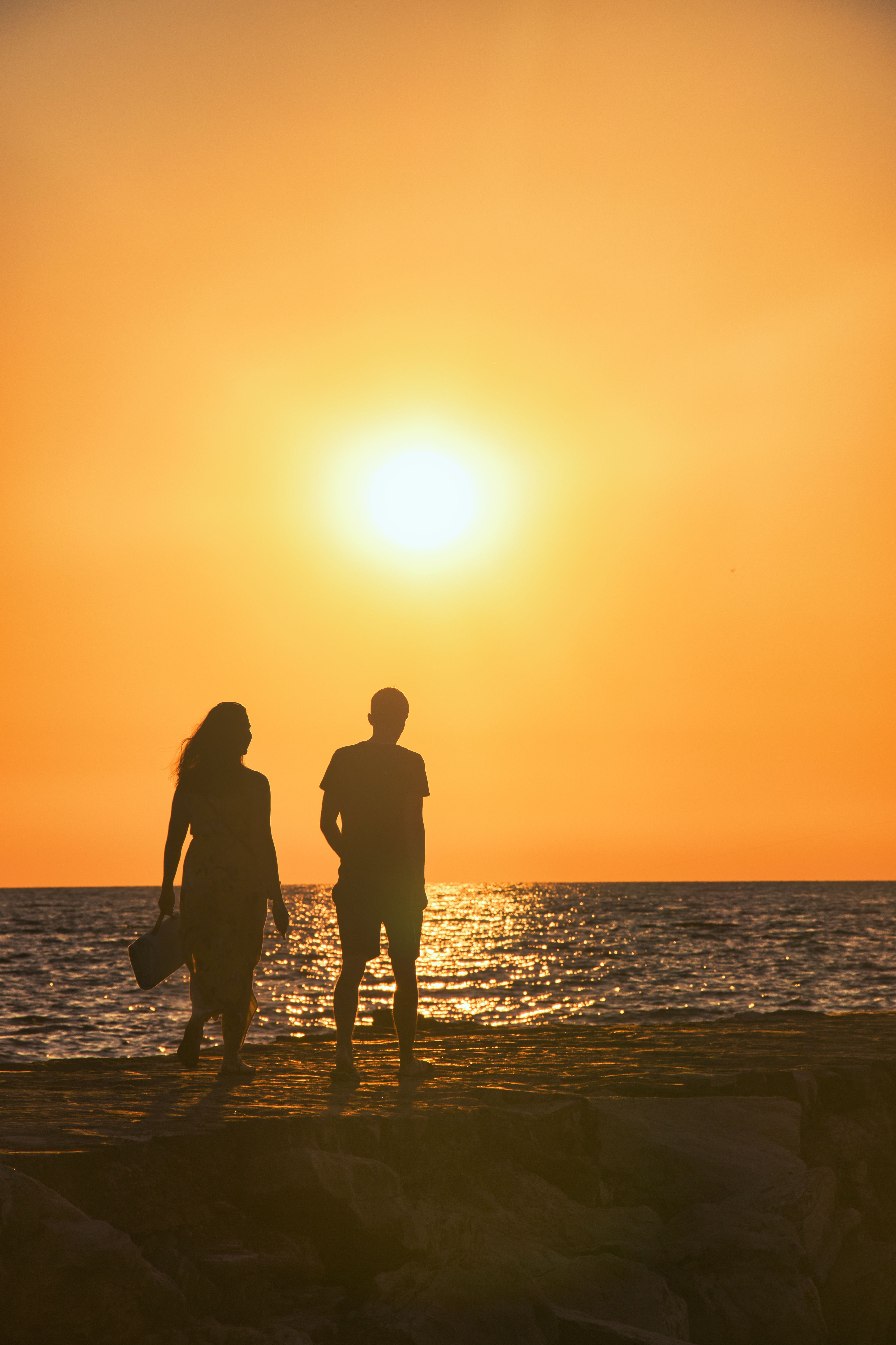 A couple walking on the beach at sunset · Free Stock Photo