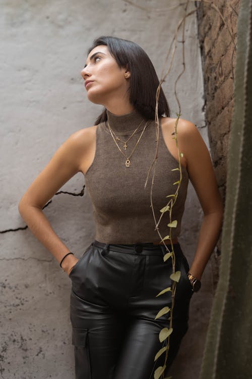 A woman in leather pants and a top leaning against a wall