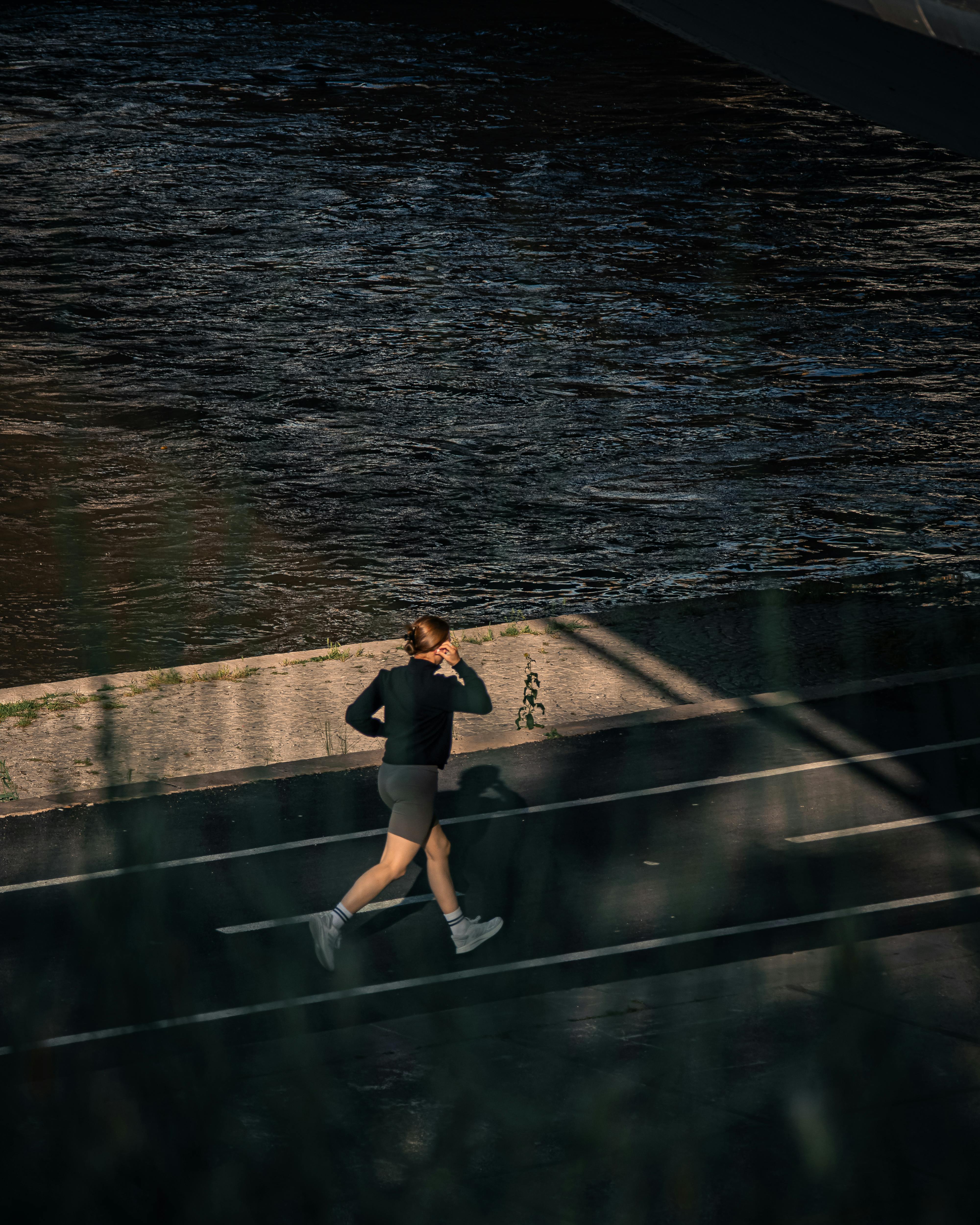 A woman in sportswear jogging along the river in Skopje, North Macedonia, captured during the day.