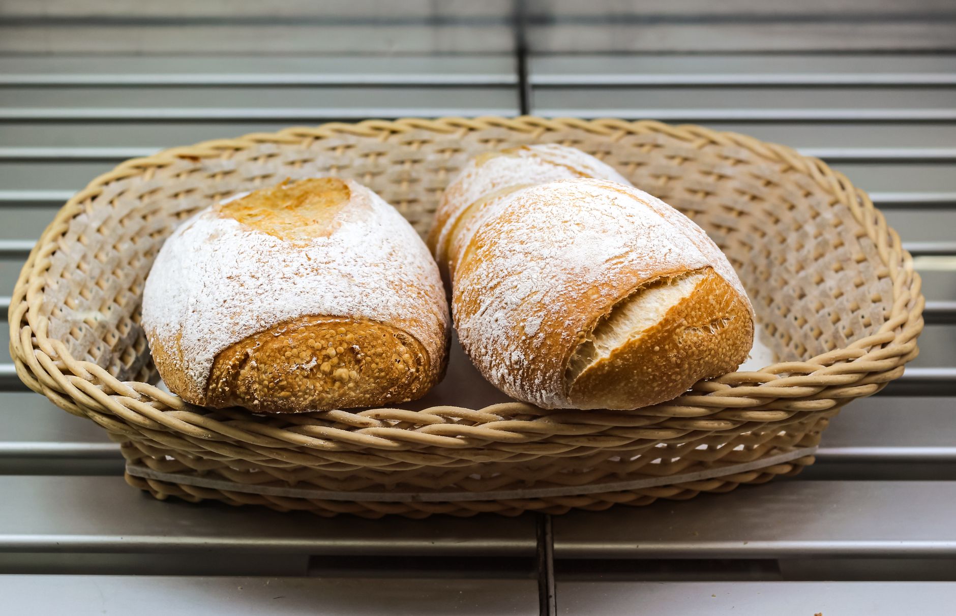Delicious artisan bread loaves with powdered sugar in a wicker basket, perfect for bakery displays.