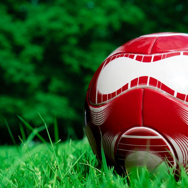Red football on grass, close view