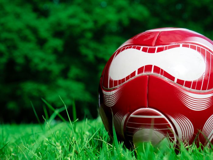 Red football resting on grass, close view
