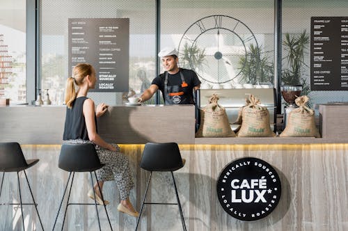 Free Woman Sitting On Bar Chair Near Barista Stock Photo